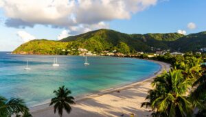 Grand Anse Beach bei Sonnenuntergang mit türkisblauem Meer, Palmen und Saint George’s Skyline.