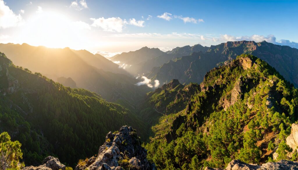 a mountain range with trees and clouds