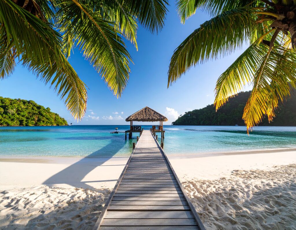 Sonnenaufgang am Pigeon Point Beach auf Tobago mit Steg und Palmen.