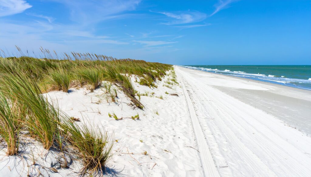 Weitläufiger weißer Sandstrand mit Dünen auf Padre Island unter blauem Himmel