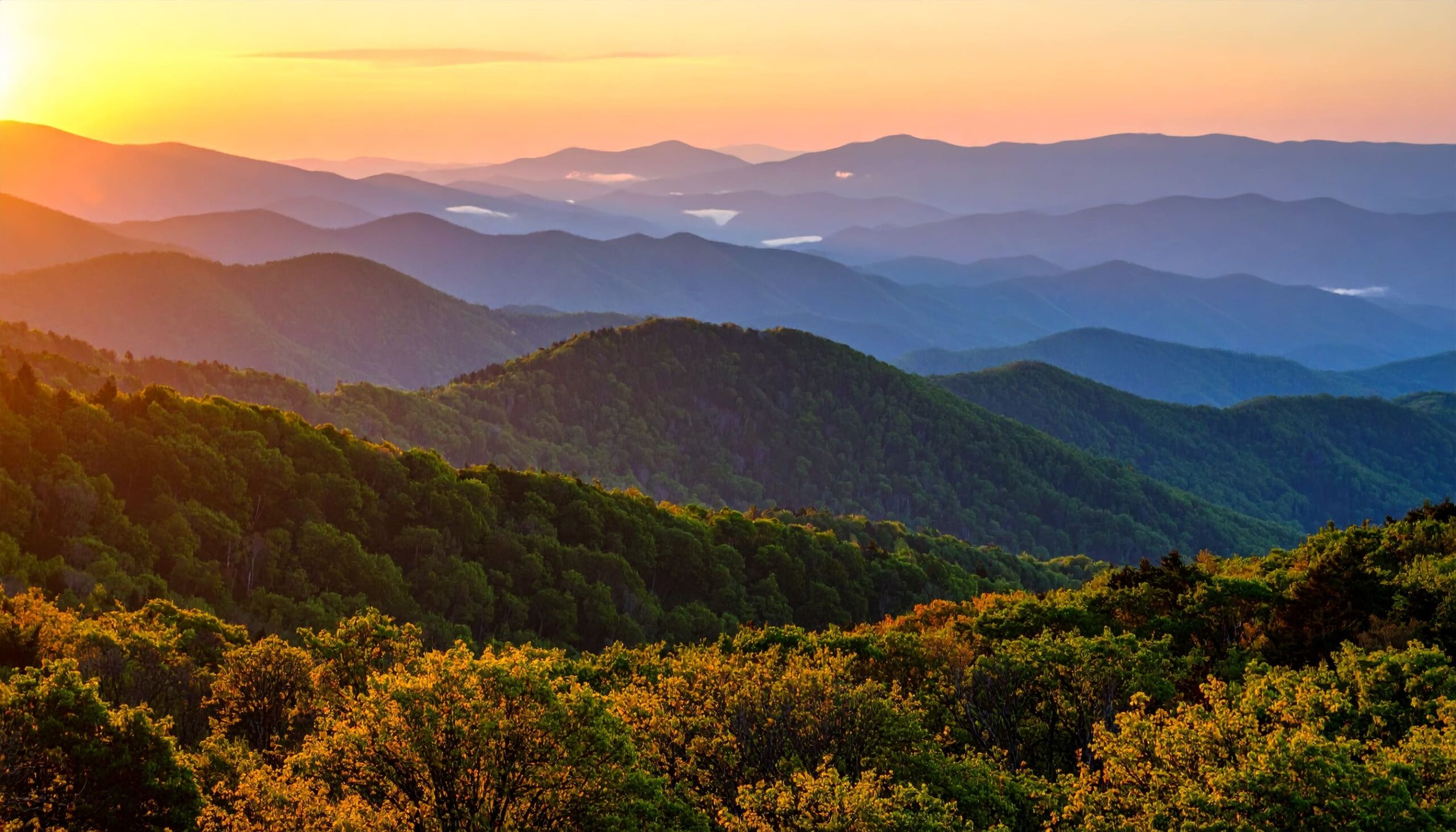 Panorama der Blue Ridge Mountains in Virginia bei Sonnenuntergang mit leuchtendem Wald und Nebel.