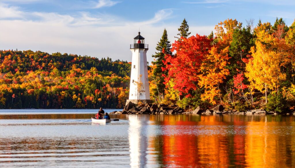 Leuchtturm und bunte Herbstwälder am Seeufer in Door County